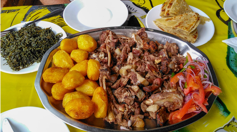 Traditional Kenyan foods platter of nyama choma, roast potatoes, kachumbari salad, with sides of sukuma wiki and chapati - Kids learn about Kenya through food