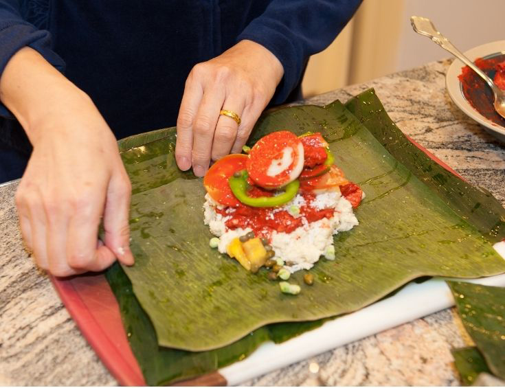 Making nacatamales - filling the banana leaves before wrapping