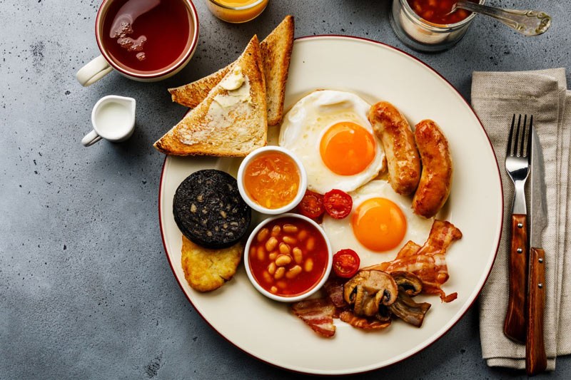 Full fry up English Breakfast: fried egg, sausage, bacon, tomatoes and onions, beans, black pudding, toast