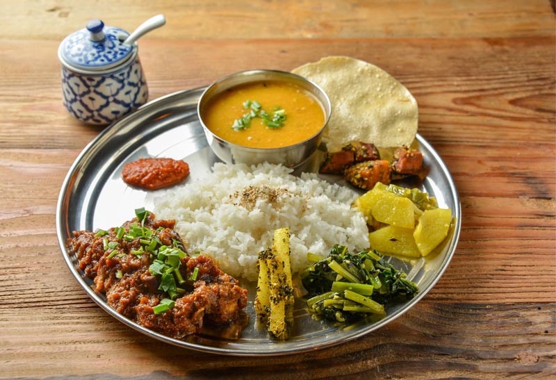 Traditional Nepali Dal Bhat - rice, dal (lentil soup), curry, assorted vegetables and greens, chutney, lavash (flatbread) - Food in Nepal for kids