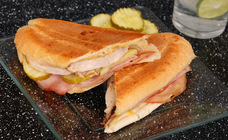 Cuban sandwich with ham, roasted pork, pickles, and Swiss cheese - Image from Canva.com